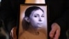 A colleague of Ukrainian journalist Viktoria Roshchyna holds a photograph of her during an event in honor of Viktoria's memory at a makeshift memorial for fallen Ukrainian soldiers, at Independence Square in Kyiv, Oct. 11, 2024. 